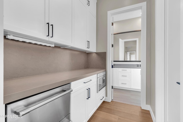 66 Caballada St, Reno, NV 89511 - kitchen with white cabinetry, light wood-style flooring, stainless steel dishwasher, and light countertops
