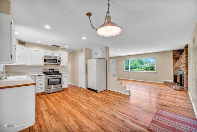 825 W 11th St, Reno, NV 89503 - kitchen featuring appliances with stainless steel finishes, light wood-style floors, light countertops, open floor plan, and white cabinets