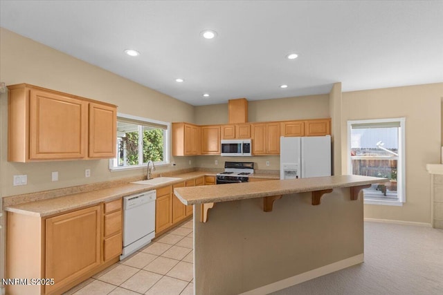 9732 Autumn Leaf Way, Reno, NV 89506 - kitchen with white appliances, a breakfast bar area, light brown cabinetry, light countertops, and recessed lighting