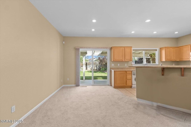 9732 Autumn Leaf Way, Reno, NV 89506 - kitchen featuring recessed lighting, light colored carpet, light countertops, a breakfast bar, and light brown cabinetry