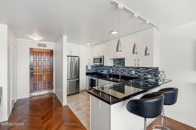 100 N Arlington Ave Unit 17G, Reno, NV 89501 - kitchen with appliances with stainless steel finishes, a peninsula, decorative backsplash, dark countertops, and a breakfast bar area