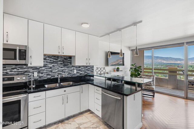 100 N Arlington Ave Unit 17G, Reno, NV 89501 - kitchen with stainless steel appliances, backsplash, white cabinetry, a peninsula, and pendant lighting