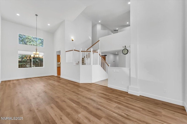 4413 Desert Hills Ct, Sparks, NV 89436 - unfurnished living room with high vaulted ceiling, a chandelier, stairs, wood finished floors, and recessed lighting