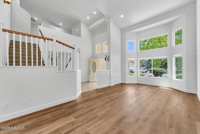4413 Desert Hills Ct, Sparks, NV 89436 - unfurnished living room featuring a towering ceiling, stairway, wood finished floors, and recessed lighting