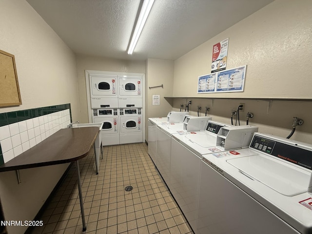 2450 Lymbery St Unit 219, Reno, NV 89509 - shared laundry with washing machine and dryer, stacked washer / drying machine, a textured ceiling, light tile patterned floors, and a textured wall