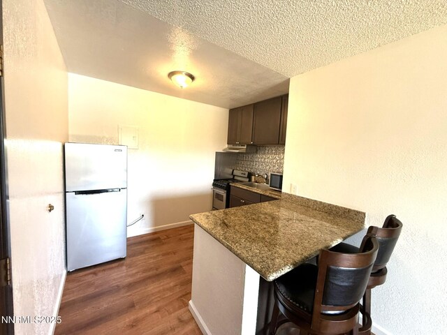 2450 Lymbery St Unit 219, Reno, NV 89509 - kitchen featuring freestanding refrigerator, high end stainless steel range oven, a textured ceiling, wood finished floors, and a peninsula