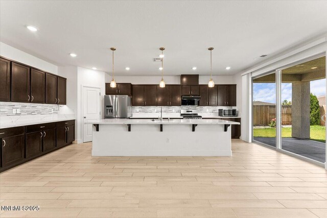 2251 Slater Mill Dr, Sparks, NV 89441 - kitchen featuring appliances with stainless steel finishes, tasteful backsplash, light countertops, a kitchen bar, and recessed lighting