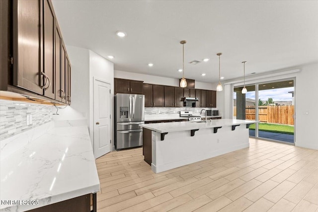 2251 Slater Mill Dr, Sparks, NV 89441 - kitchen with appliances with stainless steel finishes, tasteful backsplash, a breakfast bar, dark brown cabinetry, and recessed lighting