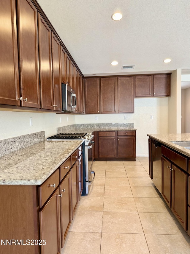 1122 Ferretto Pkwy, Dayton, NV 89403 - kitchen with stainless steel appliances, light stone counters, recessed lighting, light tile patterned floors, and dark brown cabinets