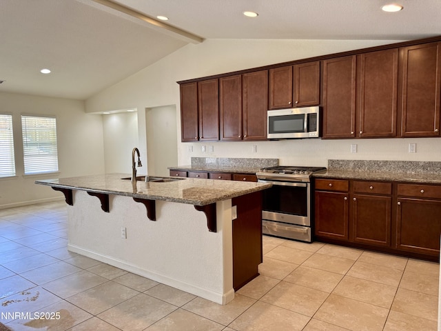 1122 Ferretto Pkwy, Dayton, NV 89403 - kitchen with appliances with stainless steel finishes, light tile patterned floors, dark stone counters, a kitchen bar, and an island with sink