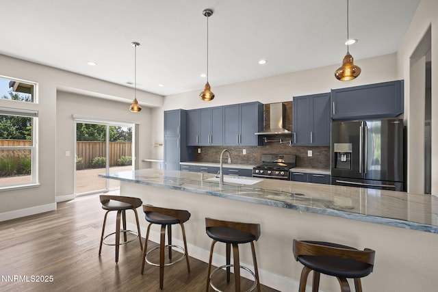 1660 Murrieta Ct, Reno, NV 89521 - kitchen featuring stainless steel appliances, wall chimney range hood, backsplash, light stone counters, and wood finished floors