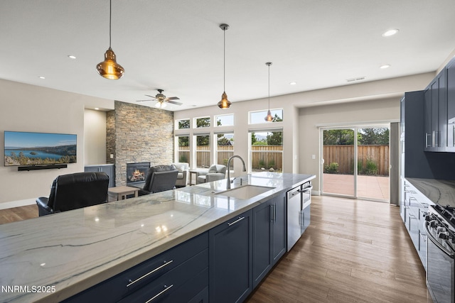 1660 Murrieta Ct, Reno, NV 89521 - kitchen with appliances with stainless steel finishes, a fireplace, light stone counters, ceiling fan, and recessed lighting