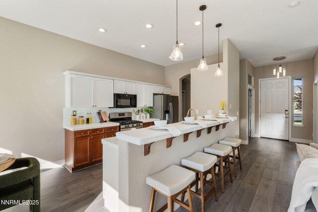 10265 Donnay Ct, Reno, NV 89521 - kitchen with appliances with stainless steel finishes, dark wood-type flooring, a breakfast bar area, a peninsula, and arched walkways