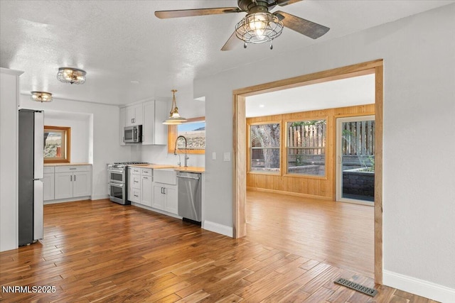 4710 Yukon Ct, Carson City, NV 89706 - kitchen featuring stainless steel appliances, wood finished floors, a ceiling fan, white cabinets, and a textured ceiling
