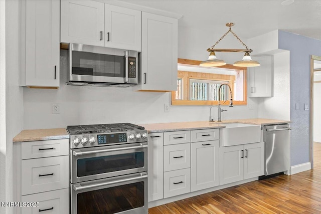 4710 Yukon Ct, Carson City, NV 89706 - kitchen featuring appliances with stainless steel finishes, light wood-style flooring, white cabinets, decorative light fixtures, and light stone countertops