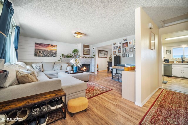 1165 Autumn Hills Dr, Reno, NV 89511 - living room with light wood-style flooring, a warm lit fireplace, a textured ceiling, and attic access