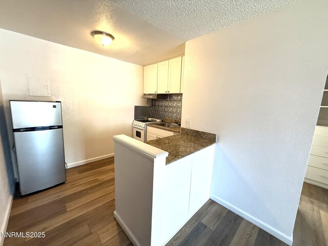 2450 Lymbery St Unit 228, Reno, NV 89509 - kitchen with freestanding refrigerator, dark countertops, a textured ceiling, dark wood-style flooring, and white cabinetry