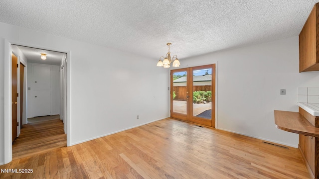 908 E Robinson St, Carson City, NV 89701 - unfurnished dining area featuring a chandelier, light wood finished floors, and a textured ceiling
