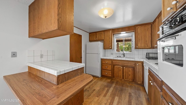 908 E Robinson St, Carson City, NV 89701 - kitchen with white appliances, brown cabinets, backsplash, and dark wood finished floors