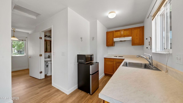 908 E Robinson St, Carson City, NV 89701 - kitchen with appliances with stainless steel finishes, under cabinet range hood, light wood finished floors, light countertops, and brown cabinets
