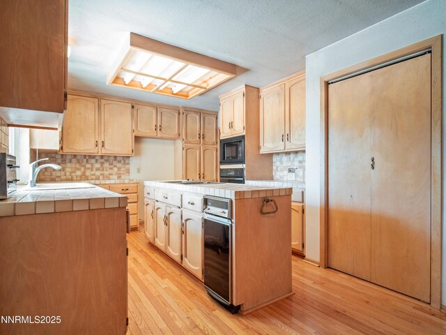1561 Alba Vis, Gardnerville, NV 89410 - kitchen featuring tile countertops, black microwave, light wood-style floors, light brown cabinets, and tasteful backsplash