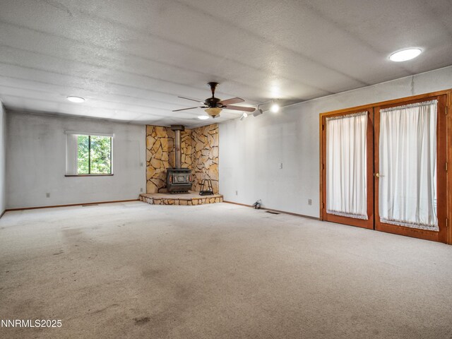 1561 Alba Vis, Gardnerville, NV 89410 - unfurnished living room featuring a wood stove, carpet flooring, a textured ceiling, and ceiling fan