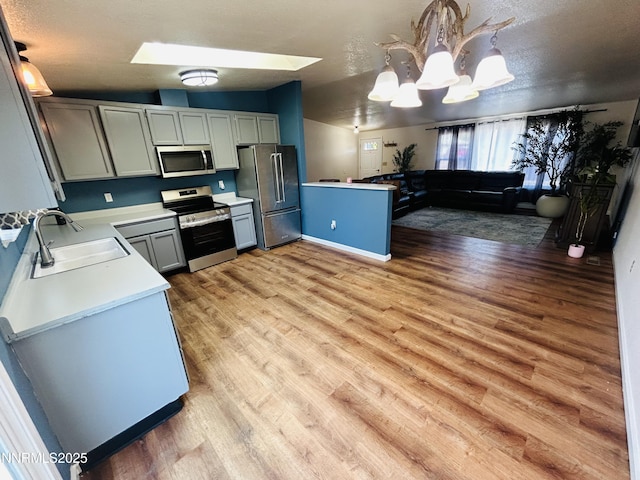 1442 Spooner Dr, Carson City, NV 89706 - kitchen with stainless steel appliances, a chandelier, light countertops, hanging light fixtures, and light wood-style flooring