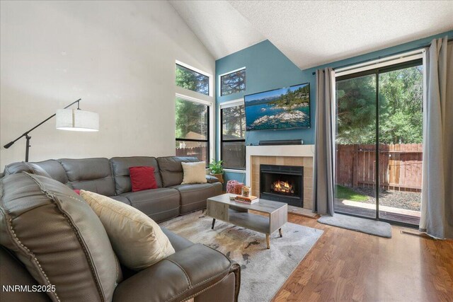 4318 Leeward Ln, Reno, NV 89502 - living area featuring wood finished floors, a tiled fireplace, plenty of natural light, high vaulted ceiling, and a textured ceiling