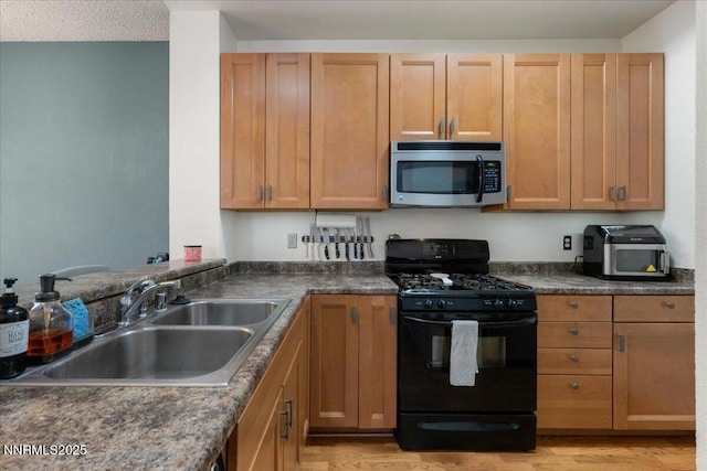 4318 Leeward Ln, Reno, NV 89502 - kitchen with black range with gas stovetop, stainless steel microwave, dark countertops, and light wood-type flooring