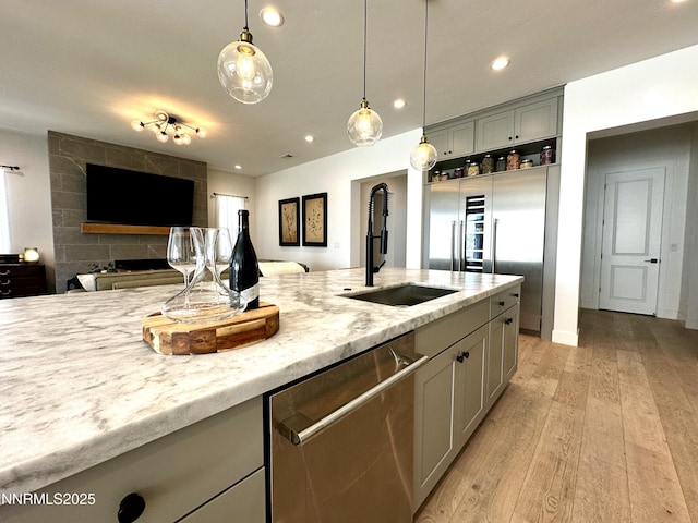5454 Side Saddle Trl, Reno, NV 89511 - kitchen featuring appliances with stainless steel finishes, open floor plan, pendant lighting, light wood-type flooring, and light stone counters