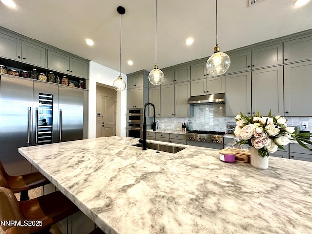 5454 Side Saddle Trl, Reno, NV 89511 - kitchen with appliances with stainless steel finishes, a kitchen bar, light stone countertops, tasteful backsplash, and hanging light fixtures