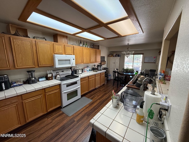 2271 Ruddy Way, Spanish Springs, NV 89441 - kitchen with white appliances, tile counters, a chandelier, and dark wood-style flooring