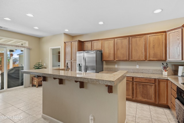 164 Oakridge Dr, Dayton, NV 89403 - kitchen with stainless steel fridge with ice dispenser, light tile patterned floors, a breakfast bar area, recessed lighting, and a center island