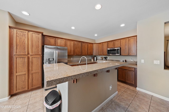 164 Oakridge Dr, Dayton, NV 89403 - kitchen with stainless steel appliances, light tile patterned flooring, a center island with sink, a breakfast bar area, and recessed lighting
