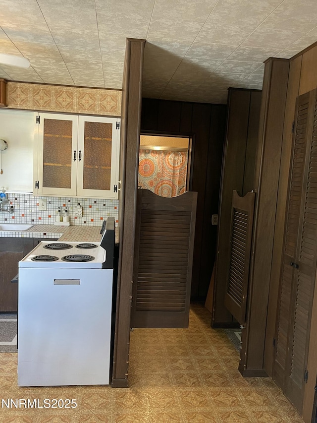 4 3rd St, Mcgill, NV 89318 - kitchen with white range with electric cooktop, tasteful backsplash, glass insert cabinets, and light floors