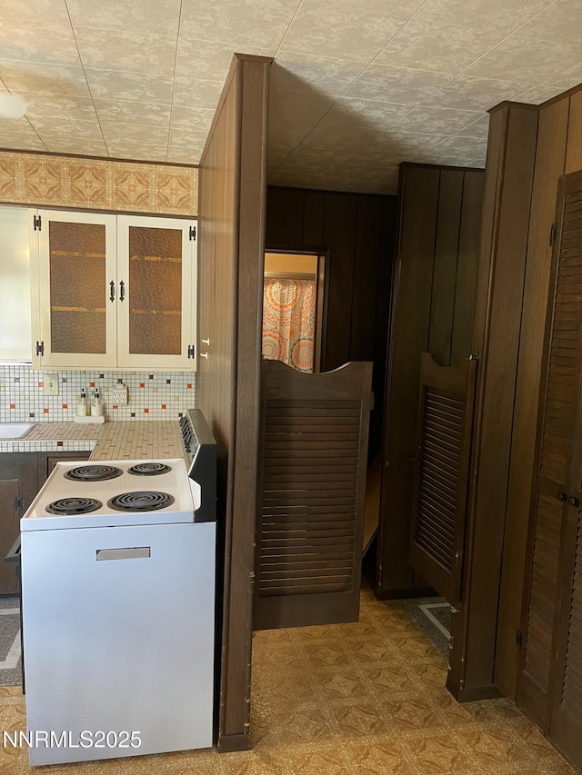 4 3rd St, Mcgill, NV 89318 - kitchen with electric stove, tasteful backsplash, glass insert cabinets, and tile patterned floors