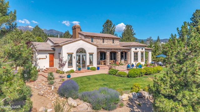 186 Carleton Ct, Reno, NV 89511 - rear view of house featuring a mountain view, a lawn, stucco siding, a chimney, and french doors