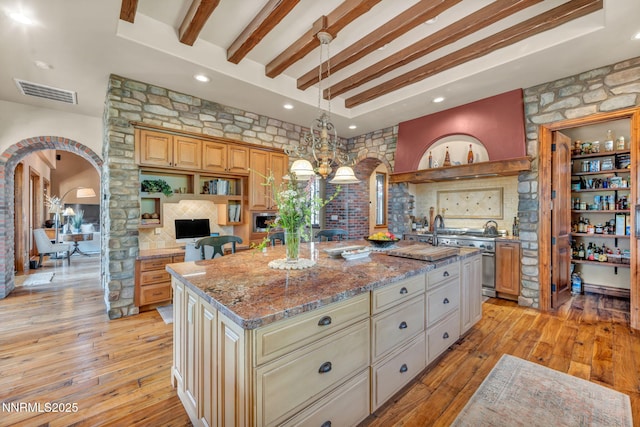 186 Carleton Ct, Reno, NV 89511 - kitchen with arched walkways, range with two ovens, beam ceiling, a kitchen island, and light stone counters