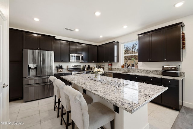 1149 Dapple Dr, Minden, NV 89423 - kitchen featuring appliances with stainless steel finishes, light tile patterned flooring, a breakfast bar, light stone counters, and recessed lighting
