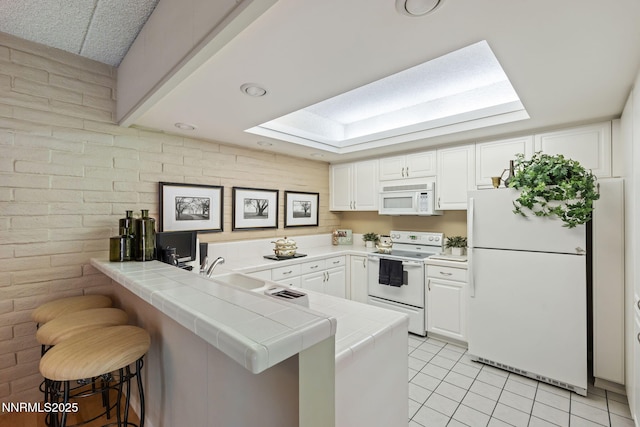 1200 Riverside Dr # 1232, Reno, NV 89503 - kitchen with white appliances, tile countertops, a peninsula, light tile patterned floors, and brick wall