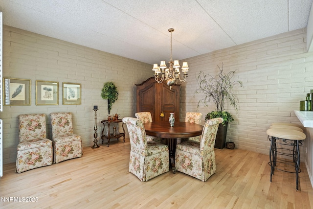 1200 Riverside Dr # 1232, Reno, NV 89503 - dining space featuring light wood-style floors, a chandelier, and brick wall