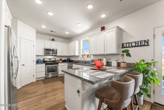 516 Beckwourth Dr, Reno, NV 89506 - kitchen with stainless steel appliances, a peninsula, light wood-style floors, white cabinets, and recessed lighting
