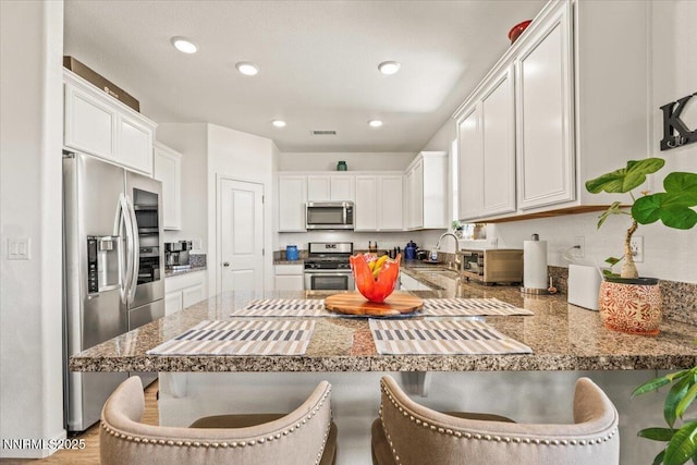 516 Beckwourth Dr, Reno, NV 89506 - kitchen featuring stainless steel appliances, a peninsula, a kitchen bar, recessed lighting, and white cabinetry