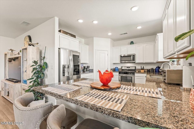 516 Beckwourth Dr, Reno, NV 89506 - kitchen featuring stainless steel appliances, a peninsula, white cabinets, a kitchen bar, and recessed lighting
