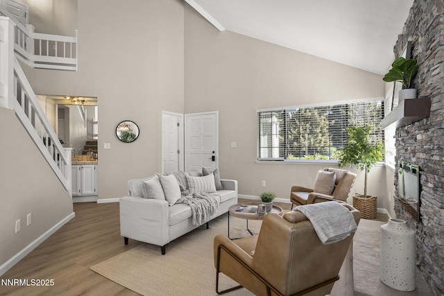 4030 Willowsprings Dr, Reno, NV 89519 - living room with a stone fireplace, stairway, light wood-type flooring, and high vaulted ceiling