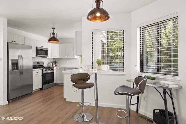 4030 Willowsprings Dr, Reno, NV 89519 - kitchen with stainless steel appliances, light wood-type flooring, a breakfast bar area, and hanging light fixtures