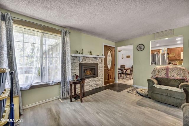 6670 Lotus St, Reno, NV 89506 - living room featuring a textured ceiling, wood finished floors, and a stone fireplace