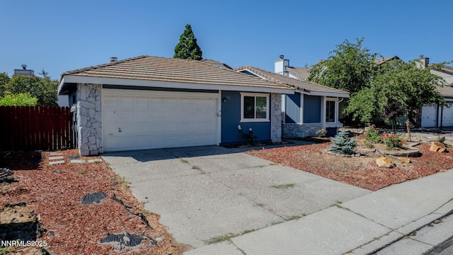 777 W Bonanza Dr, Carson City, NV 89706 - view of front of home with stone siding, a garage, concrete driveway, a chimney, and a tiled roof