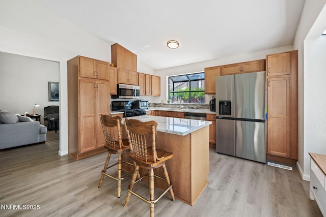 777 W Bonanza Dr, Carson City, NV 89706 - kitchen with stainless steel appliances, vaulted ceiling, light wood finished floors, light stone counters, and a kitchen breakfast bar