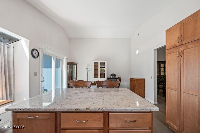 777 W Bonanza Dr, Carson City, NV 89706 - kitchen with dark wood-type flooring, lofted ceiling, a kitchen island, light stone countertops, and brown cabinetry
